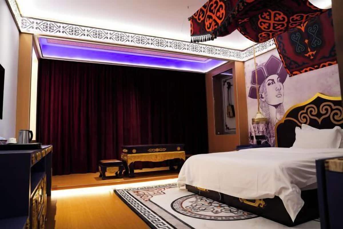A room with a bed, a desk, a chair, a red curtain, and a patterned carpet.
