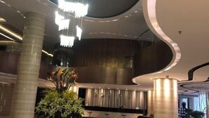 Un hall d’entrée moderne avec un plafond incurvé, un comptoir d’accueil et un grand lustre.