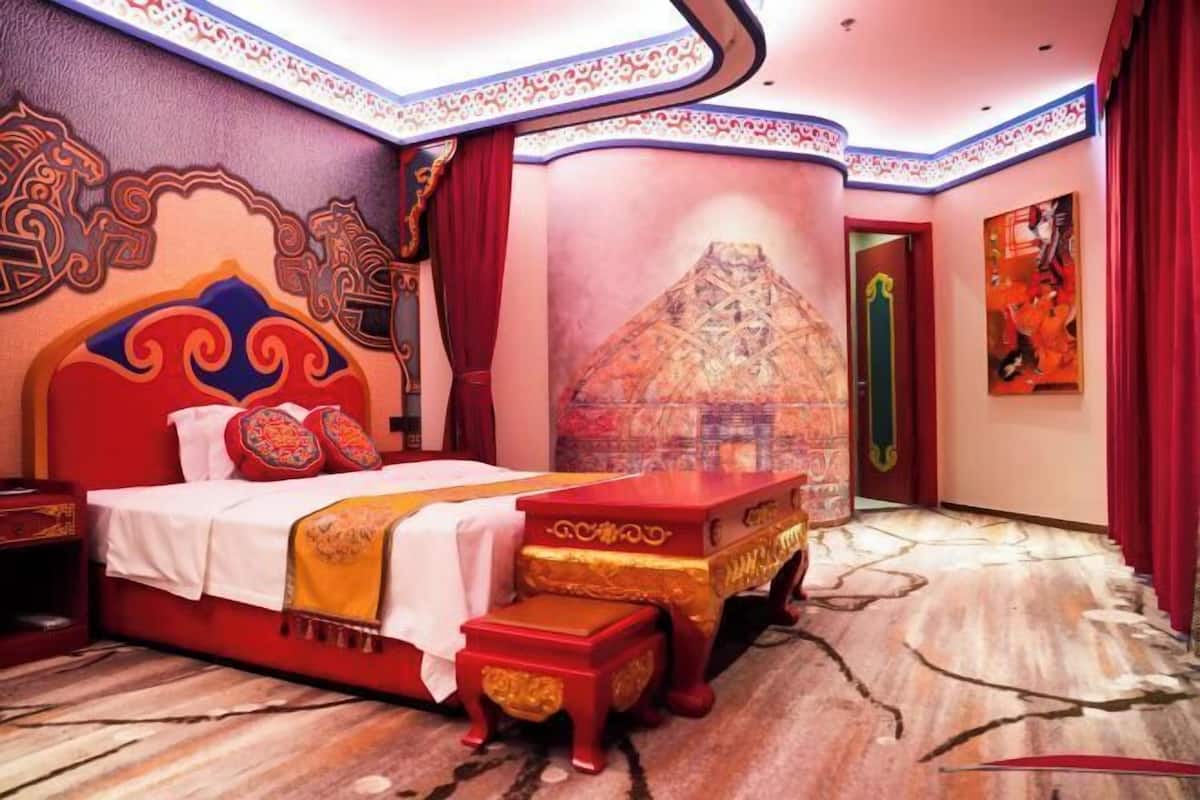 A traditional room with a bed, a red table, and a wall mural.