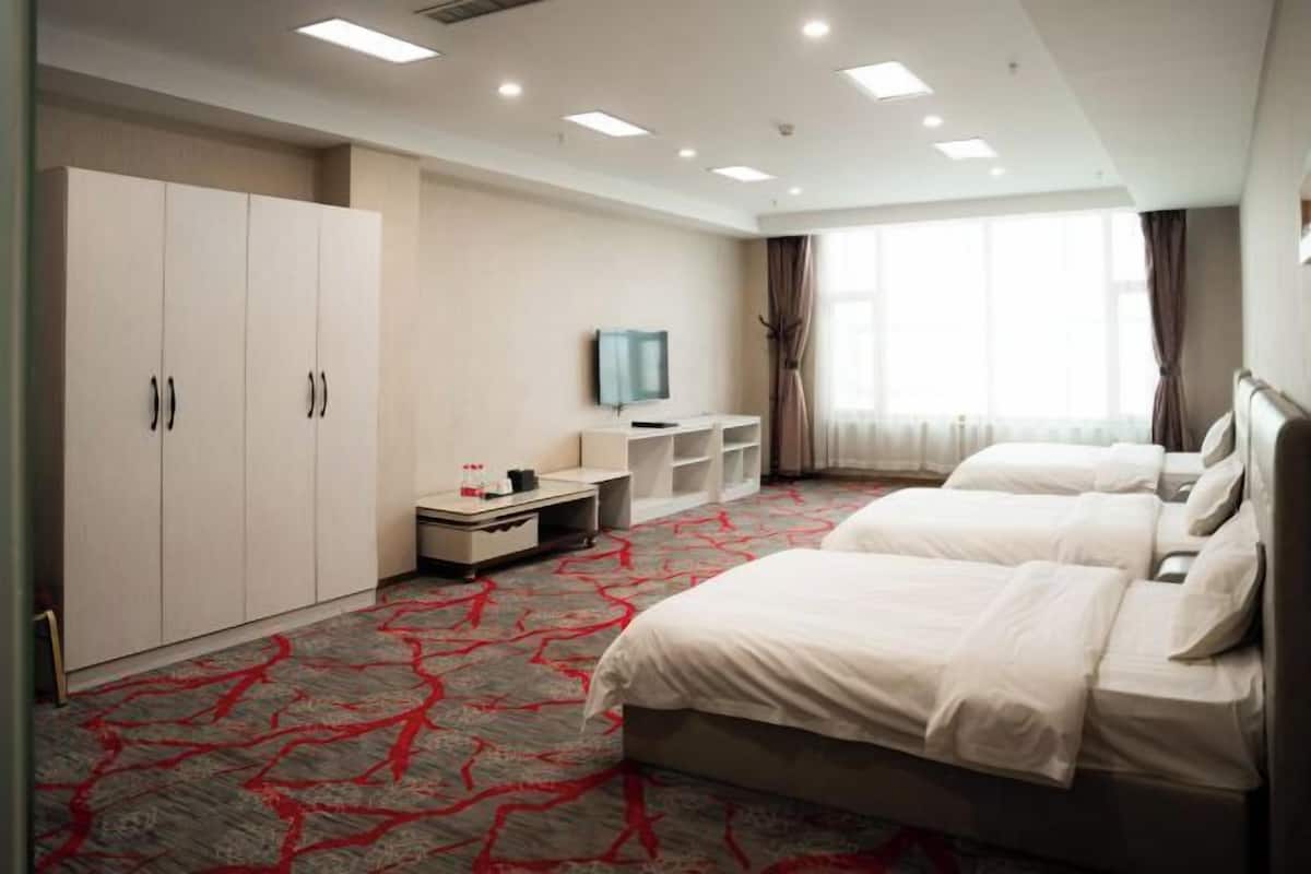A hotel room with two beds, a TV, a desk, and a wardrobe.