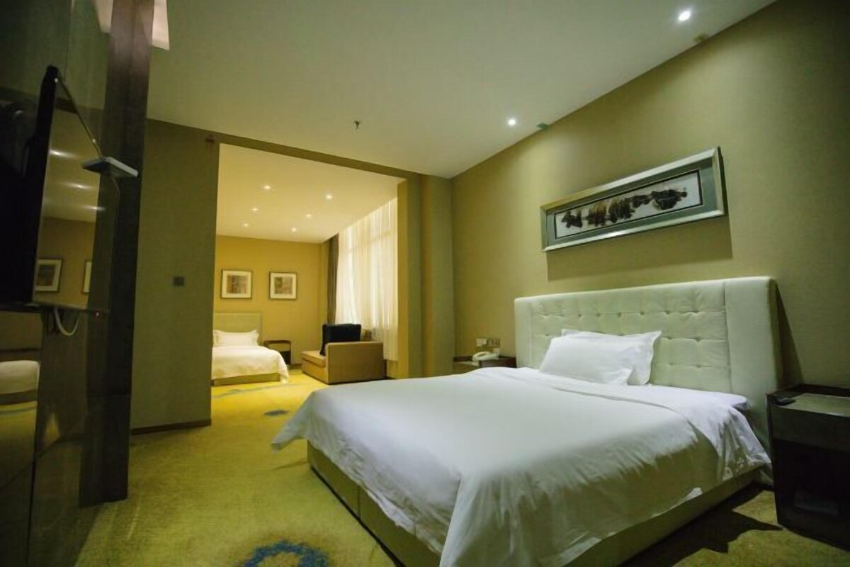 Une chambre d’hôtel avec un grand lit, une table de chevet, une chaise et un tableau encadré au mur.