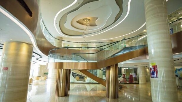 Un intérieur moderne avec un escalier en colimaçon central, des rampes en verre et un plancher poli.