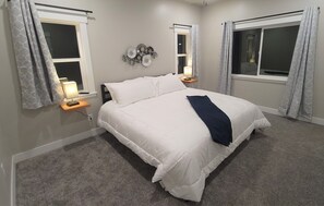 A bedroom with a large bed, two bedside tables with lamps, a wall decoration, and a window with curtains. - Kanab, Utah, Family, Outdoor Space, Zion's, Bryce, Grand Canyon, Best Friends (Kanab)