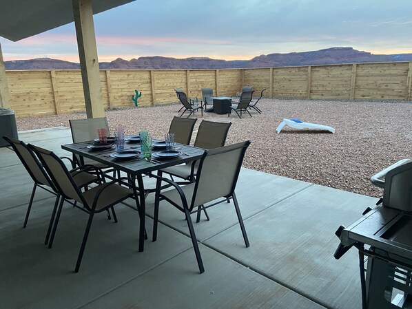 An outdoor patio with a table set for dining, surrounded by chairs, and a view of the mountains in the background. - Kanab, Utah, Family, Outdoor Space, Zion's, Bryce, Grand Canyon, Best Friends (Kanab)