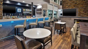 Un área de bar moderna con mostrador, asientos y pared de piedra.