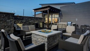 Un patio al aire libre con muros de piedra, muebles de mimbre y una chimenea integrada.