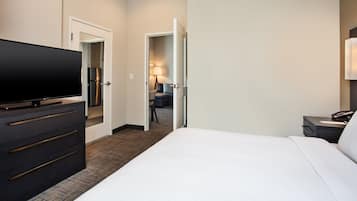 Una habitación de hotel con una cama grande, un televisor en una cómoda, un escritorio con lámpara y una puerta que da al baño.