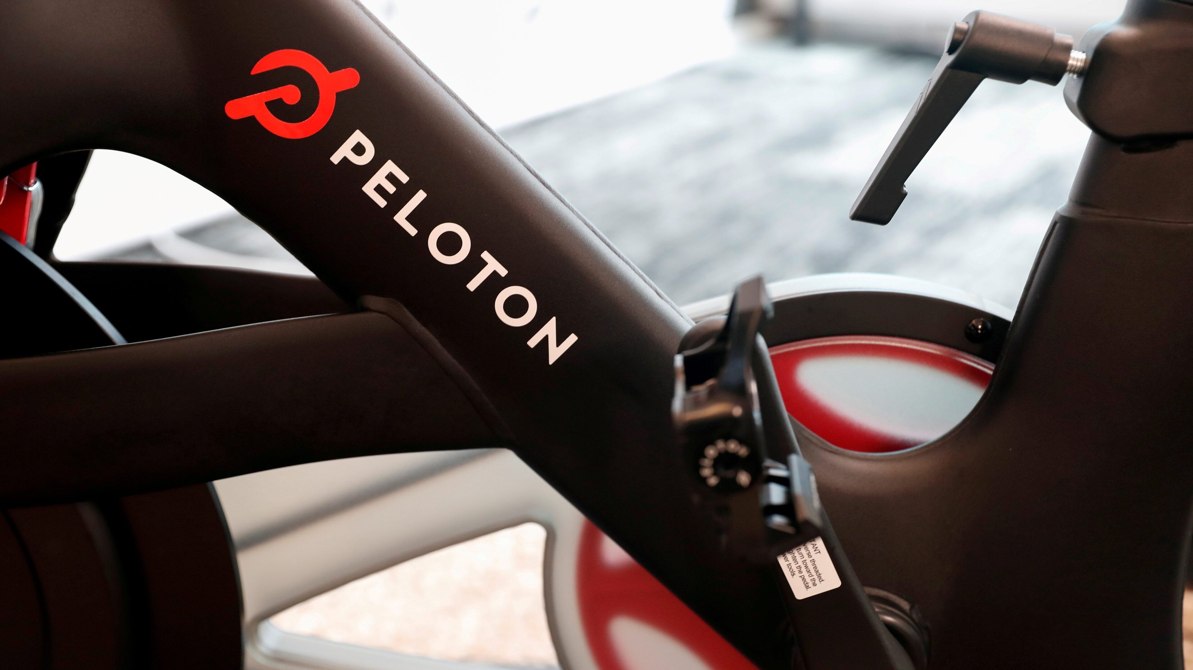 A close-up of a Peloton exercise bike with a black frame and red accents.