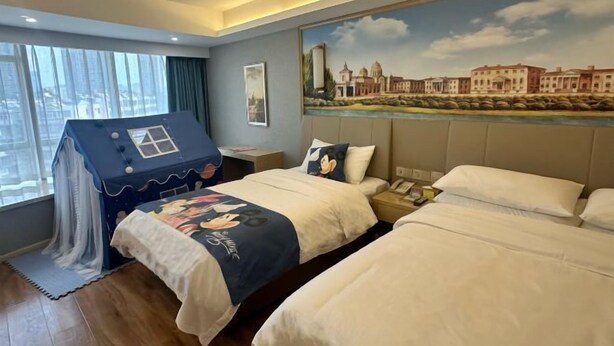 A hotel room with two beds, a large window with curtains, a mural on the wall, and a small play tent. - Vienna Hotel (Kunming Baiyun Road Metro Station Jiang'an) (Kunming)