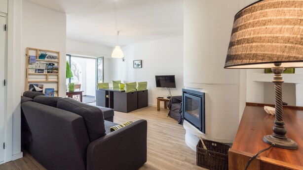 Una sala de estar moderna con sofá, televisor, chimenea y lámpara.