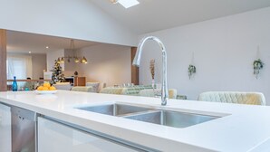Cocina moderna con encimera blanca, lavaplatos de acero inoxidable y lavavajillas integrado.