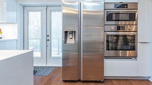 Una cocina moderna con refrigerador de acero inoxidable, horno Bosch y dispensador de agua.