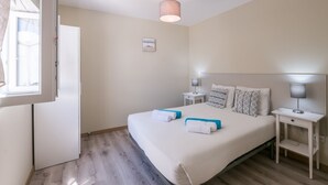 Ein Hotelzimmer mit einem großen Bett, zwei Nachttischen, einem Fenster und einer Tür.