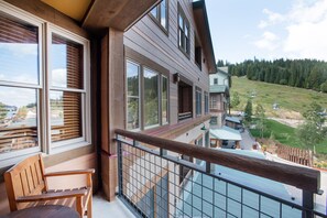Enjoy breathtaking views of the surrounding mountains from this balcony, featuring a comfortable bench and large windows.