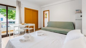 Ett hotellrum med en säng, en grön soffa, ett bord med stolar och ett fönster med gardiner.
