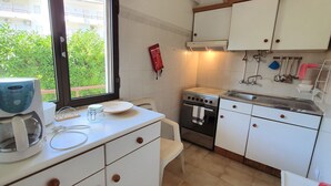 A compact kitchen with white cabinets, a stove, and a coffee maker. - Lovely Algarvian Escape by LovelyStay (Manta Rota)