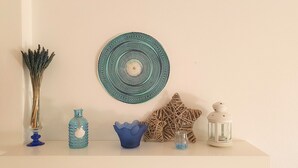 A shelf with decorative items including a woven plate, a blue vase, a glass bottle, a blue bowl, a star-shaped object, and a white lantern. - Lovely Algarvian Escape by LovelyStay (Manta Rota)