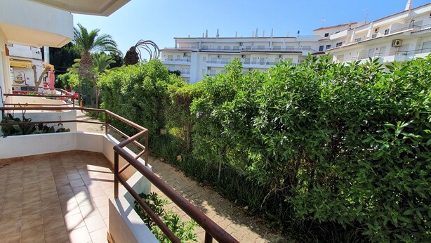 A residential building with a balcony, a garden area with dense foliage, and a clear blue sky. - Lovely Algarvian Escape by LovelyStay (Manta Rota)