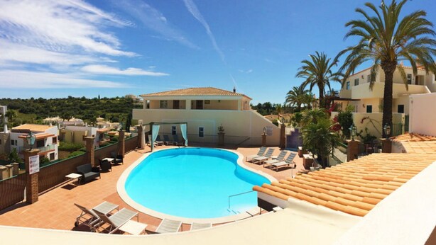 A swimming pool with lounge chairs, a covered area, and a building with a tiled roof. - 2BR  Duplex Townhouse w/Pool by LovelyStay (Ferragudo)