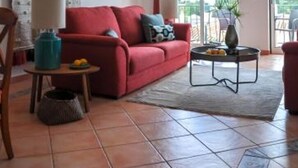 A living room with a red sofa, a coffee table, and a view through large sliding doors to an outdoor area. - 2BR  Duplex Townhouse w/Pool by LovelyStay (Ferragudo)