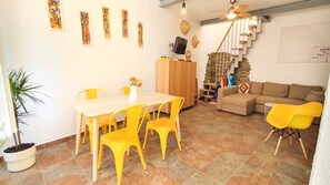 A dining area with a table and chairs, a sofa, and a staircase.