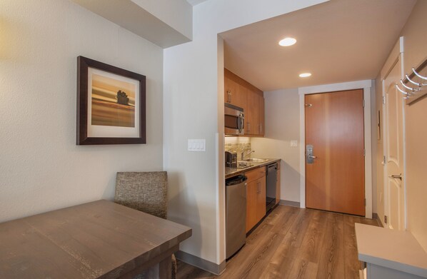 A compact kitchen with wooden cabinets, a built-in microwave, and a dishwasher. - Fraser Crossing/Founders Pointe, Studio Apartment (Premium-Rated Condo 3320) (Winter Park)