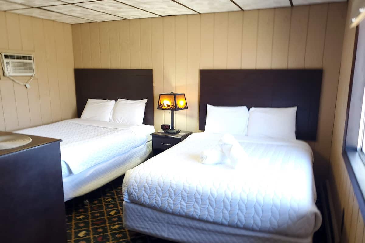 Ett hotellrum med två sängar, ett nattduksbord med en lampa och en mönstrad matta.