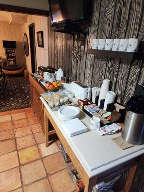 A kitchen area with a wooden countertop, a microwave, a toaster, and a variety of food items and utensils.