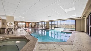 Une piscine intérieure avec un jacuzzi, de grandes fenêtres et une vue sur les montagnes.