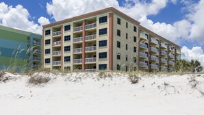 Un hôtel à plusieurs étages doté de balcons, situé près d’une plage de sable.