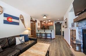 Relax in a warm and inviting living space with a comfortable sofa, stone fireplace, and ample counter space for meal preparation.