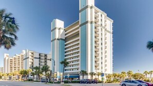 A multi-story hotel with a modern design, featuring balconies on each floor and a clear view of the surrounding palm trees. - Boardwalk Resort Condo Ocean-front Balcony 🏊 Pool 🏊 (Myrtle Beach)