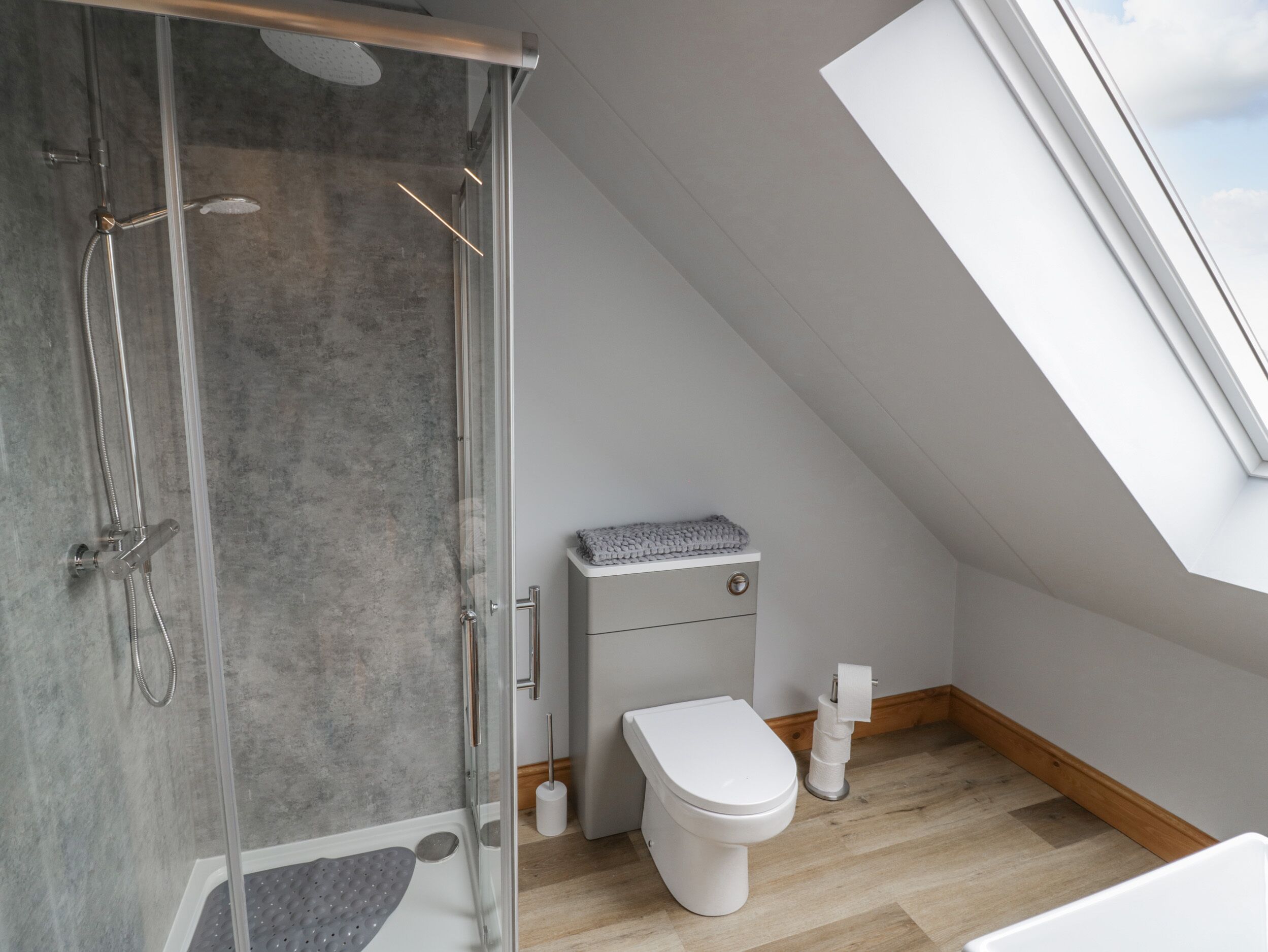 Un bagno moderno con doccia, WC e finestra a lucernario.