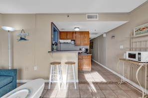 Efficient kitchen space with a dining area, featuring a microwave and stools.