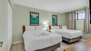 A hotel room with two beds, a wooden table, and artwork on the walls.
