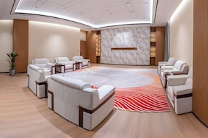 A modern hotel lobby with a reception desk, seating area, and a large, patterned rug.