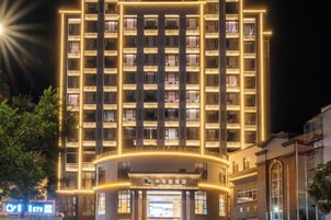 Un hotel de varios pisos con una entrada central y una serie de balcones.