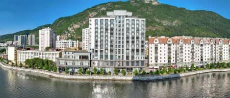 Un hotel de diseño moderno, ubicado junto a un río, con vistas a una colina al fondo.