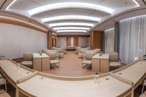 A conference room with a curved layout, multiple tables, and chairs. - Shihaolou Hotel (Gejiu)