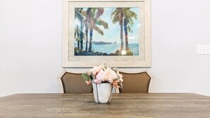 A dining table with a vase of flowers and a framed painting above it. - 20% OFF Monthly | 10% OFF Weekly-Breathtaking Condo with Excellent Amenities (New Orleans)