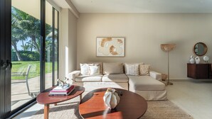 Una sala de estar moderna con sofá, mesa de centro y un amplio ventanal con vistas a un jardín.