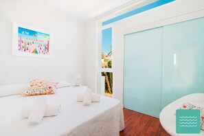 A hotel room with a bed, a pillow, a nightstand, and a view of the outside.