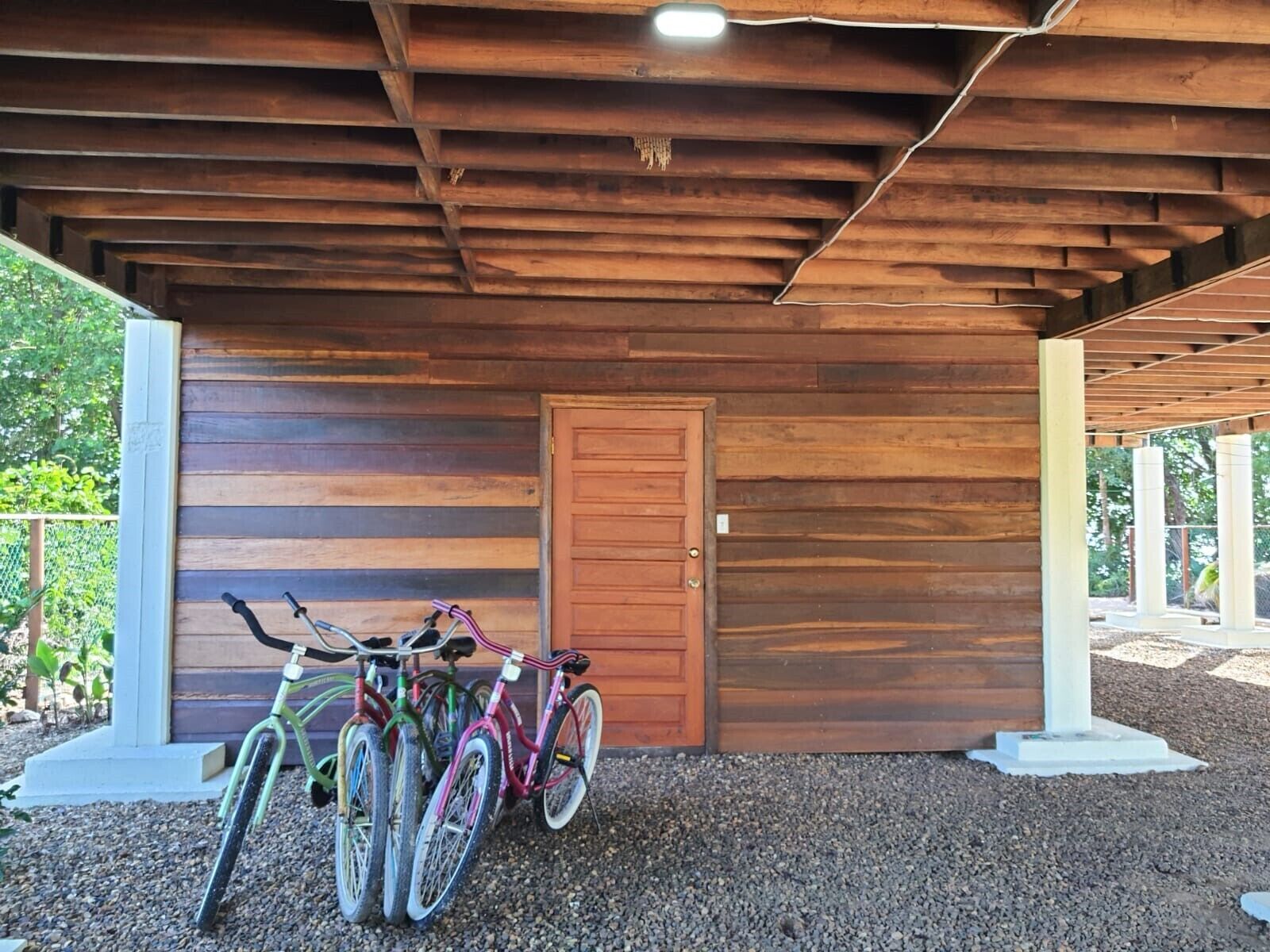 A covered outdoor area with wooden walls and a door, featuring bicycles parked against the wall.