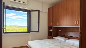 Un dormitorio con cama, armario de madera y ventana con vistas al verdor.