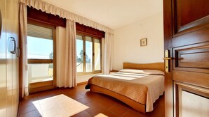 A bedroom with a bed, curtains, a window, and a door. - [Panorama] View and Comfort a few steps away from the beach (Orosei)