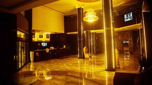 Un hall d’entrée avec un comptoir de réception, un grand lustre et un écran de télévision.