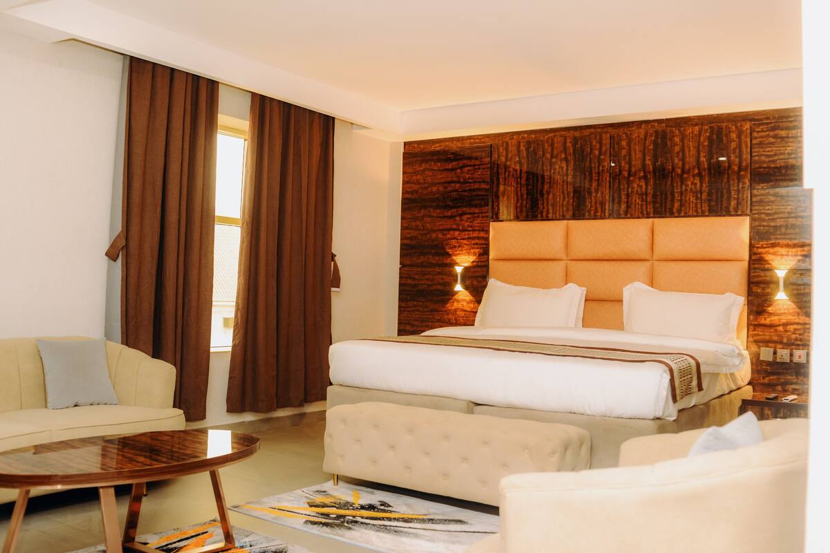 Ein Hotelzimmer mit einem großen Bett, einer Schlafcouch, einem kleinen Tisch und einer Wand mit Holzverkleidung.