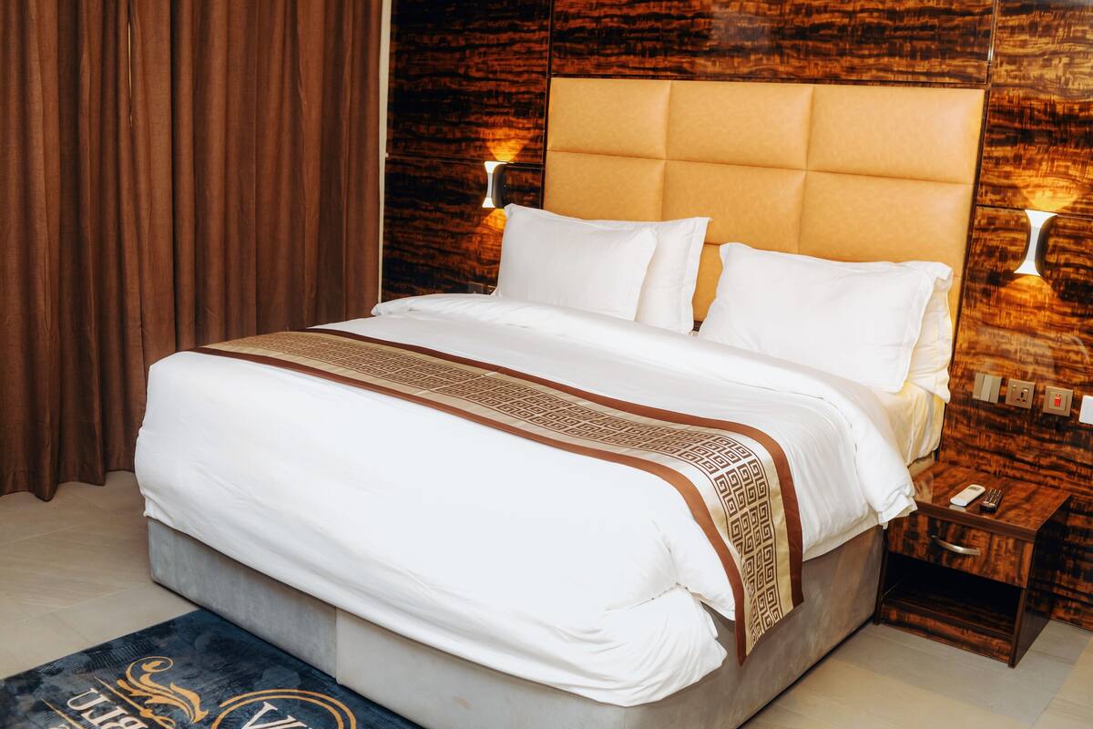 Ein Hotelzimmer mit einem großen Bett, einem Holzkopfende und einem Nachttisch mit einer Lampe.