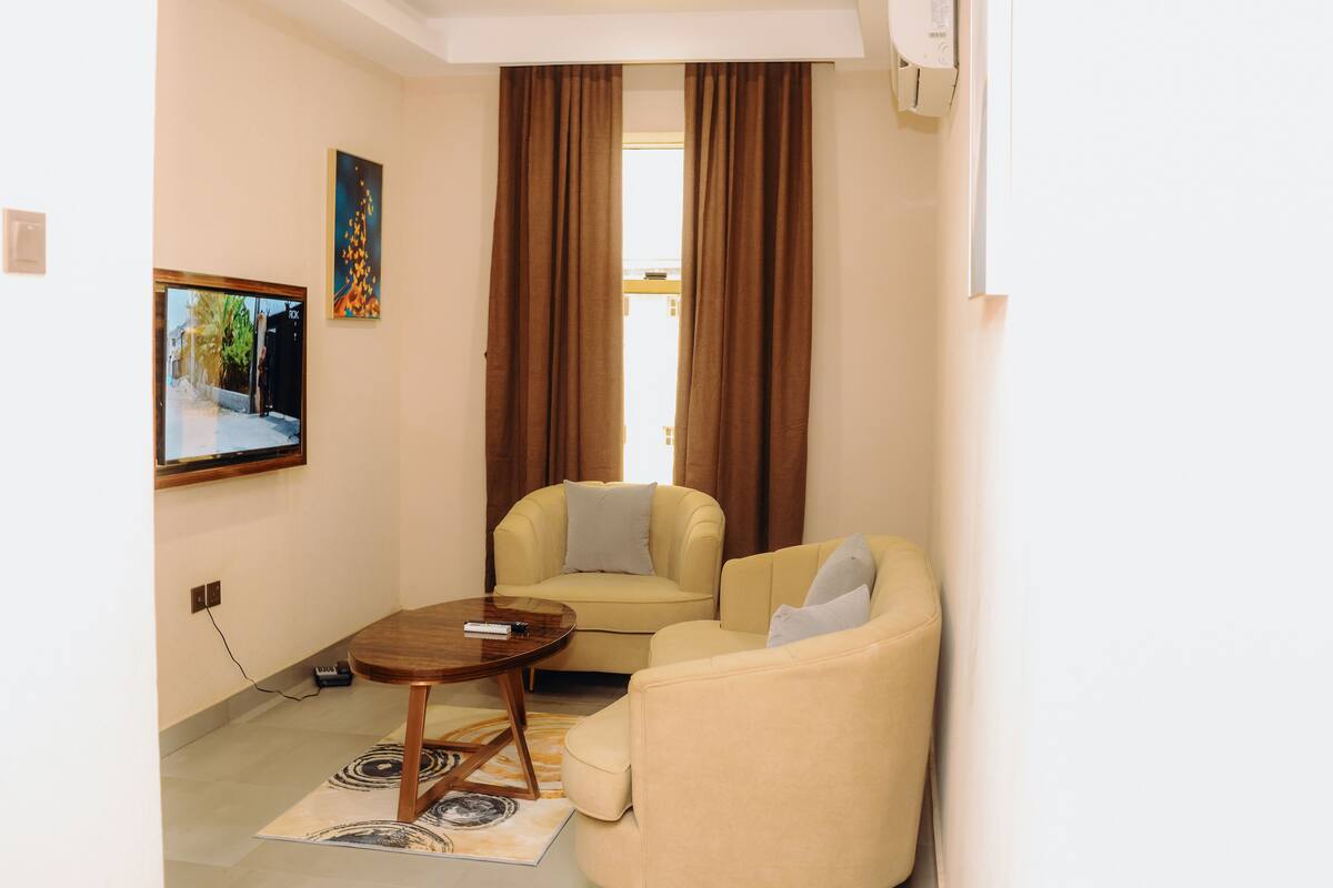 Ein Wohnzimmer mit einer Couch, einem Couchtisch, einem Gemälde und einem Fenster mit Vorhängen.