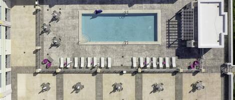An aerial view of a rooftop pool area with multiple seating areas and a pool.